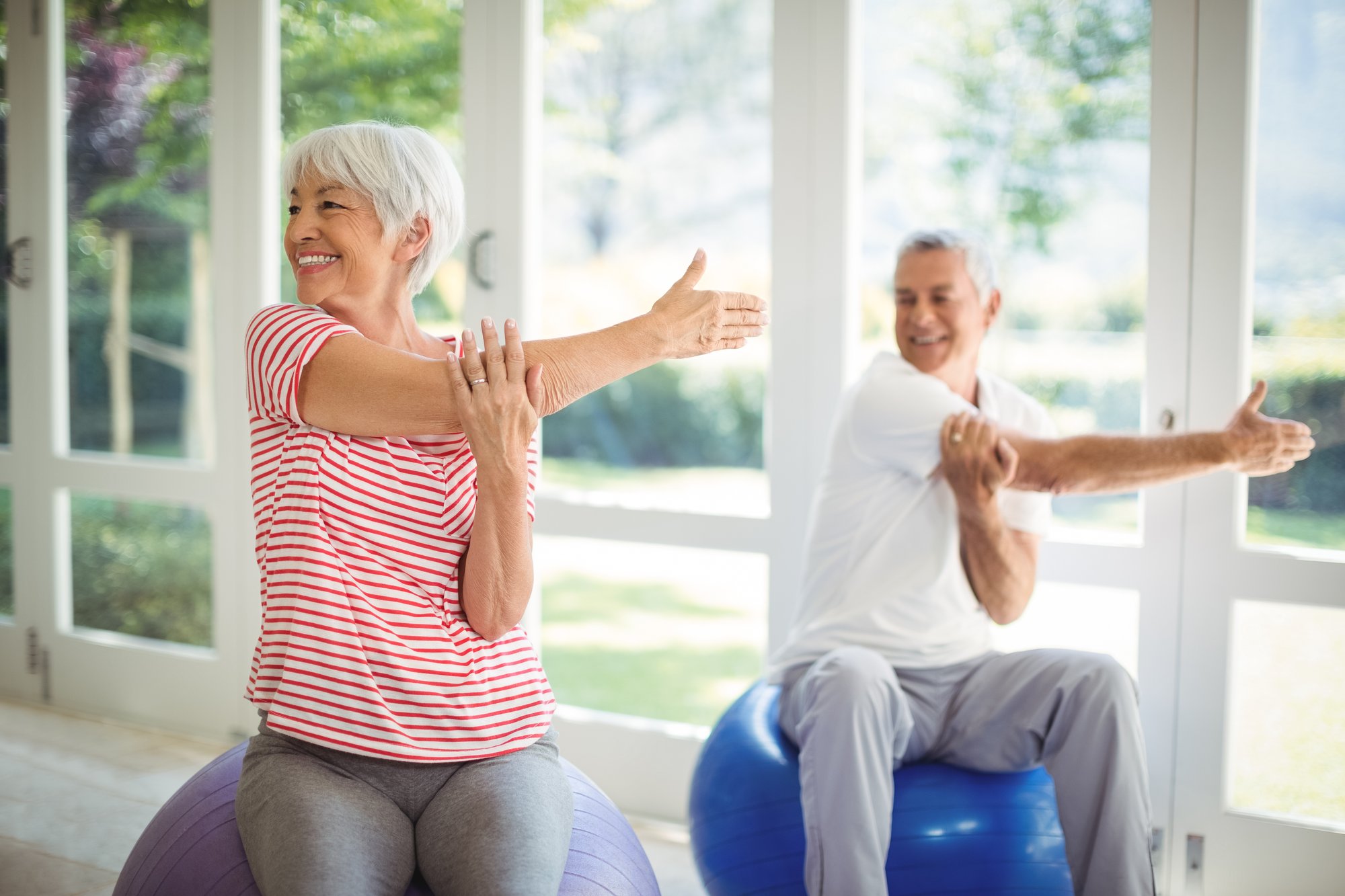 senior-couple-performing-stretching-exercise-fitness-ball